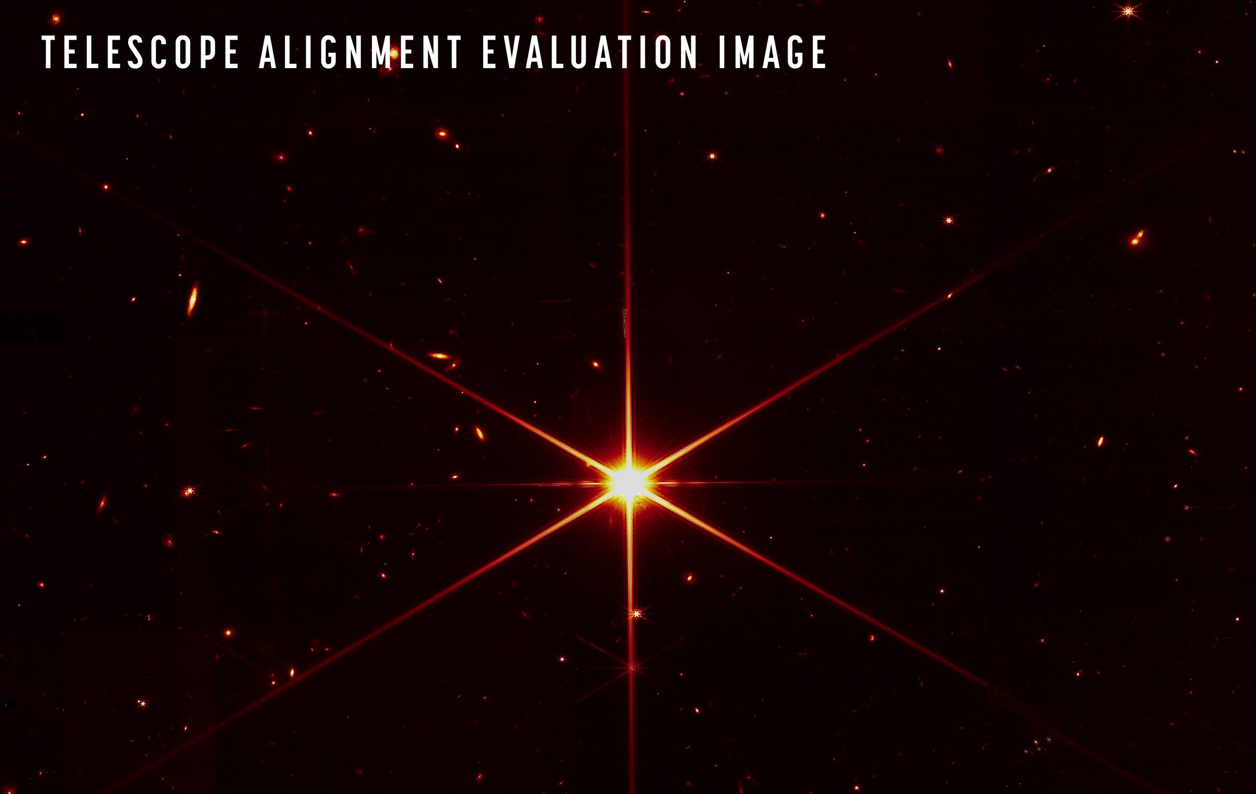 La prima foto della stella 2MASS J17554042+6551277 realizzata grazie all'allineamento di tutti i 18 specchi. Le ottiche del Webb sono talmente sensibili da poter rilevare anche le galassie sullo sfondo. La tonalità rossa è un filtro, inserito per ottimizzare il contrasto visivo. Credits: NASA/STScI
