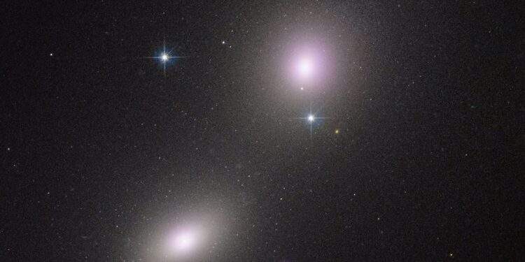Immagine del telescopio spaziale Hubble di una coppia di galassie: NGC 6099 (in basso a sinistra) e NGC 6098 (in alto a destra). Il "blob" viola raffigura l'emissione di raggi X da un ammasso stellare compatto. I raggi X sono prodotti da un probabile buco nero di massa intermedia che fa a pezzi una stella. Credits: NASA, ESA, CXC, Yi-Chi Chang (National Tsing Hua University)